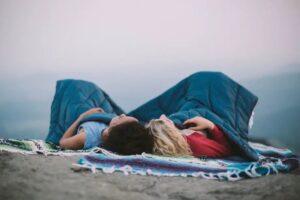 Rumpl Puffy Blanket being enjoyed by two women, lying on a rock